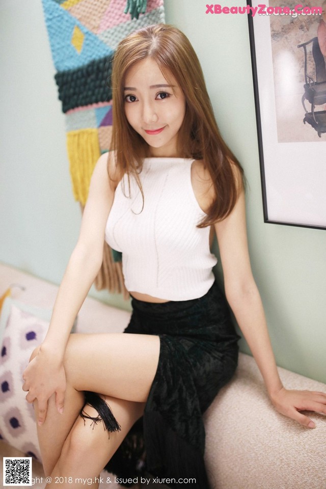 A woman sitting on top of a couch next to a wall.