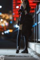 A woman in a black dress is walking down the street.