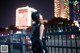 A woman standing in front of a fence at night.