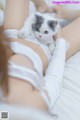 A woman laying on a bed holding a white and gray cat.