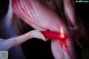 A woman holding a red candle with blood on it.