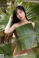 A woman in a bikini posing in front of a palm tree.