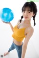 A woman in a yellow top holding a blue ball.