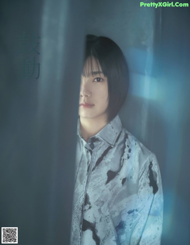 A man in a white shirt standing in front of a window.