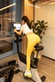 A woman in yellow leggings is riding a stationary bike.