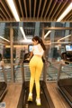 A woman in a white top and yellow leggings running on a treadmill.