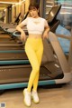 a woman in a white top and yellow leggings standing on a tread machine