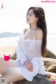 A woman sitting on top of a rock next to the ocean.