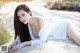 A woman laying on the sand in a white dress.