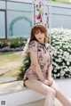 A woman sitting on a bench in front of a flower garden.