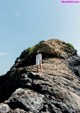 A woman standing on top of a large rock.