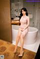 A woman in a pink dress sitting in a bathtub.