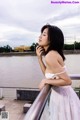 A woman in a white dress leaning against a railing.