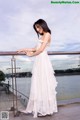 A woman in a white dress leaning on a railing.