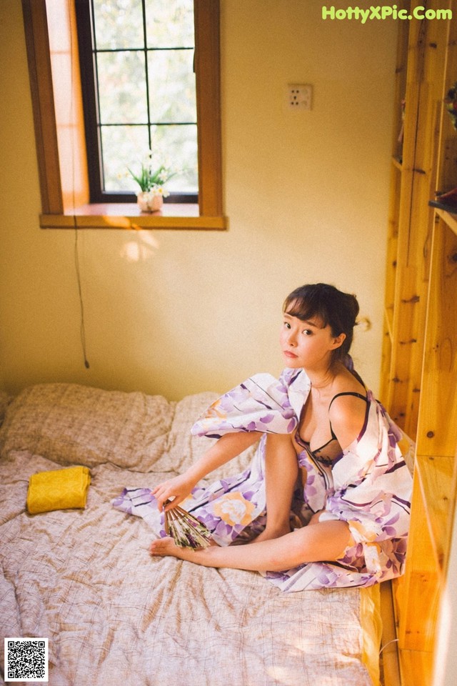 A woman sitting on a bed in a room.