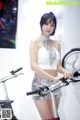 A woman standing next to a bike in a room.