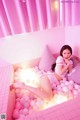 A woman laying in a pink bathtub filled with pink balls.