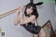 A woman in a black dress and bunny ears posing on a pole.