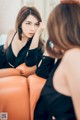 A woman sitting on a couch looking at herself in the mirror.