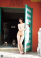 A naked woman standing in front of a green door.