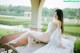 A woman in a white dress sitting on a wooden bench.