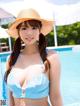 A woman in a blue bikini and a straw hat by a pool.