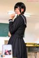 A woman in a school uniform standing in front of a laptop computer.