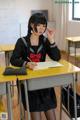 A woman in a school uniform sitting at a desk.