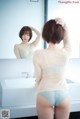 A woman standing in front of a mirror in a bathroom.