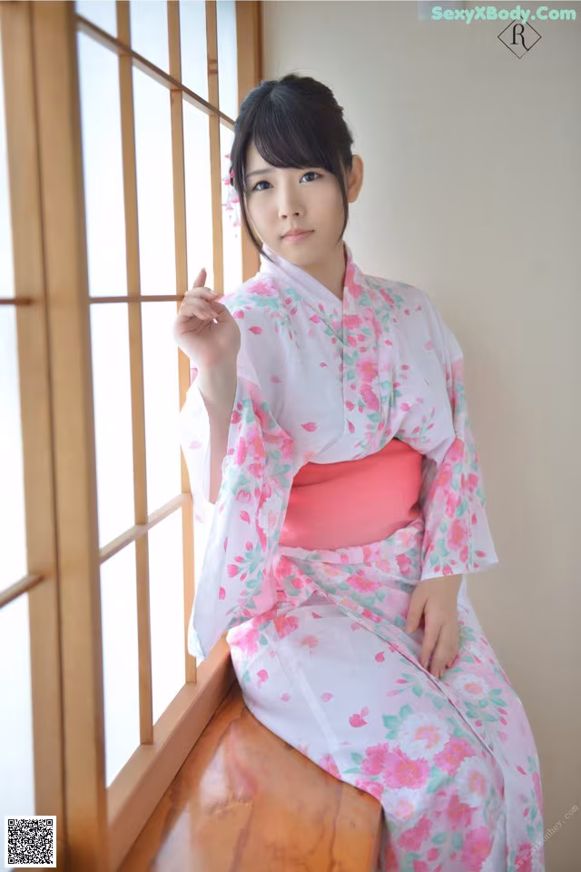 A woman in a pink and white kimono sitting on a window sill.