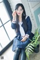 A woman in a school uniform sitting on a window sill.