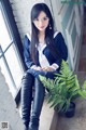 A woman in a school uniform sitting next to a plant.