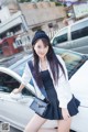 A woman standing next to a white car on a city street.