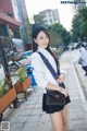 A woman in a white jacket and black skirt posing for a picture.