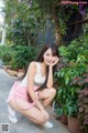 A woman in a white tank top and pink shorts posing for a picture.