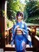 A woman in a blue kimono standing on a wooden bridge.