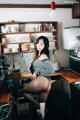 A woman sitting on top of a counter in a kitchen.